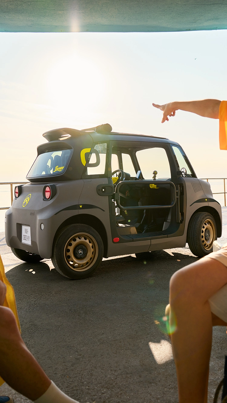 Zijaanzicht van een strand en een Citroën Ami, die een compact, veilig en betrouwbaar elektrisch ontwerp laat zien en innovatieve zomerse vrijheid biedt.