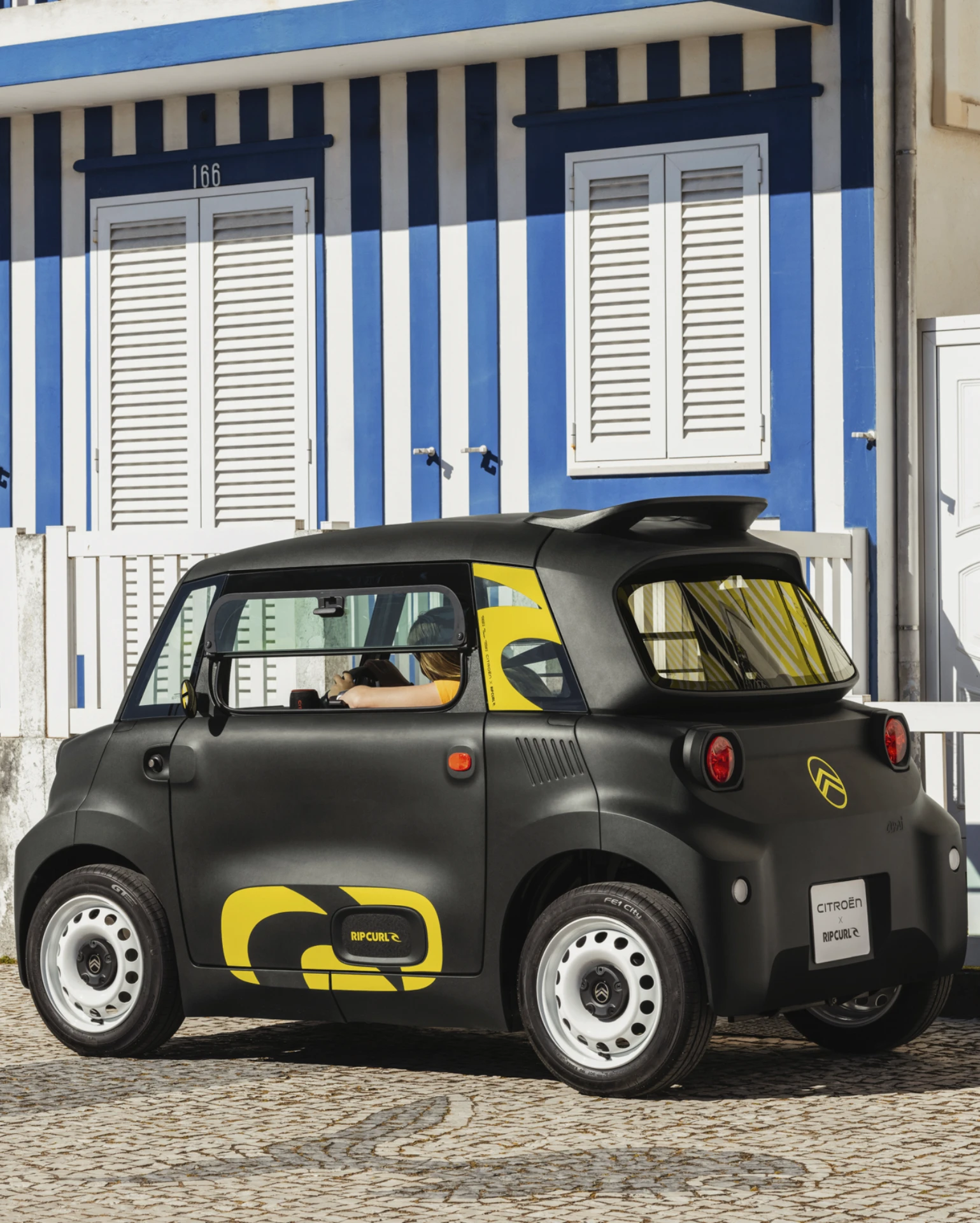 Vue arrière latérale en rue de la Citroën Ami x Rip Curl électrique sans permis, Citroën Ami synonyme de sécurité à quatre roues pour une voiture électrique urbaine