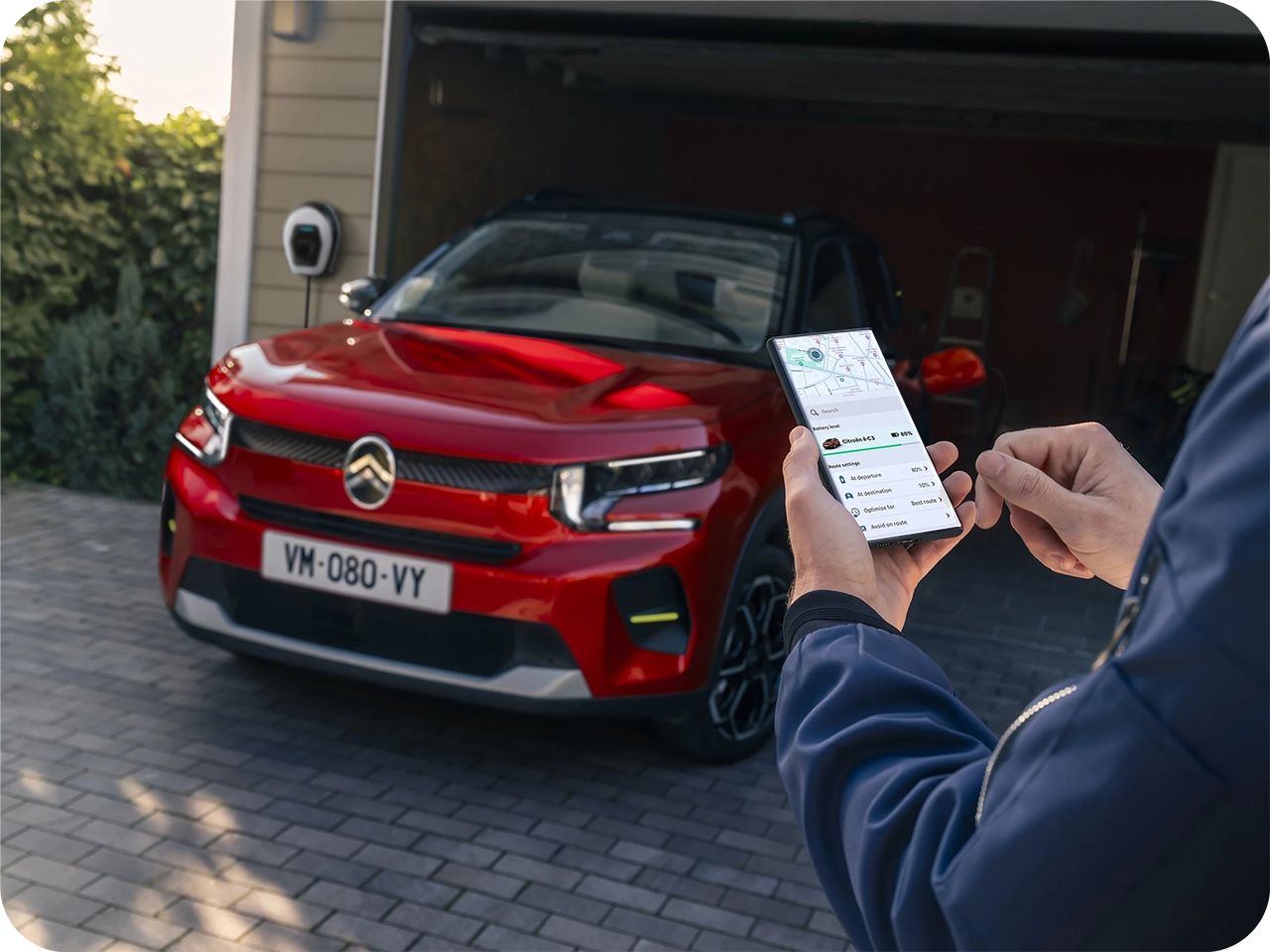 Citroën-voertuig geparkeerd terwijl een smartphone-app wordt gebruikt om voertuigfuncties op afstand te bedienen